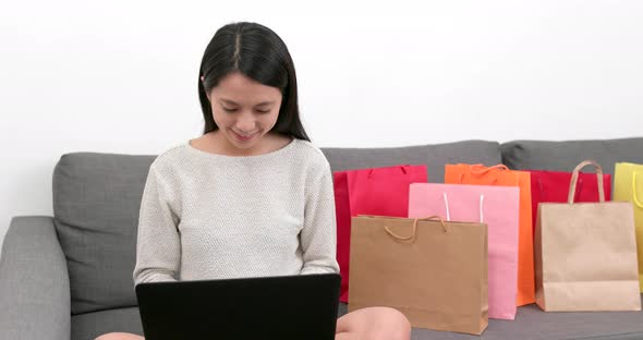 Shopping woman use of notebook computer with lots shopping bag at home