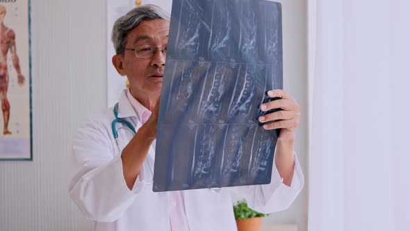 Specialist doctor examining x-ray film of patient in examination room at hospital