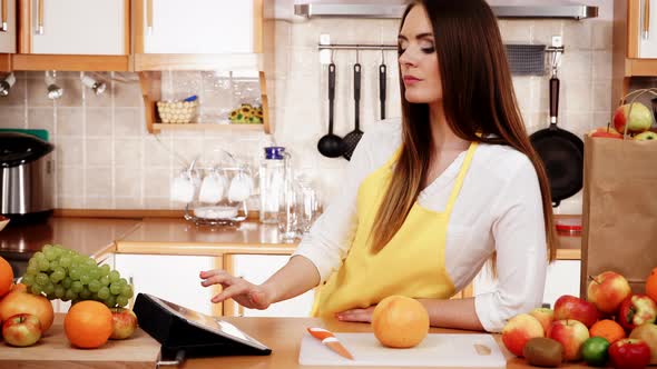 Woman in Kitchen with Fruits Using Tablet