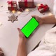 Cute girl in Santa hat holding smartphone with green screen on Christmas background - VideoHive Item for Sale
