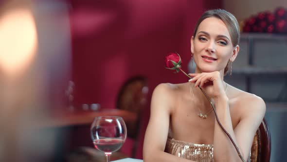 Romantic Woman Posing with Rose and Bocal Wine at Luxury Restaurant