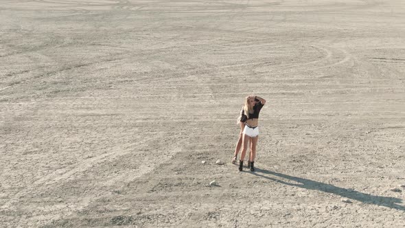 AERIAL Shot Two Slender Young Women Is Standing and Posing in the Middle of the Desert