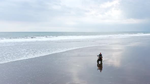 Man in Riding Motorcycle on Beach. Vintage Motorbike on Beach Sunset on Bali. Young Hipster Mal