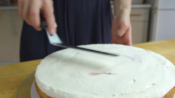 Close up of woman hands making sweet cake with white cream and biscuit.