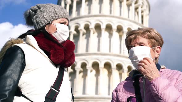 Two Women Talking Outdoor with Face Masks in Front of a Landmark