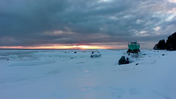 A ship on the shore of a frozen white sea at sunset. Aerial