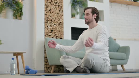 Young Man Meditating on Yoga Mat at Home