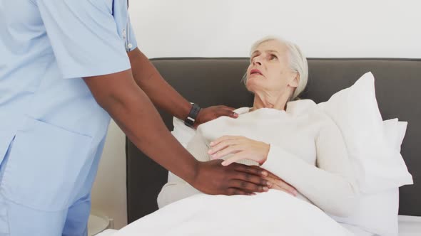 Video of midsection of african american male doctor supporting caucasian senior woman