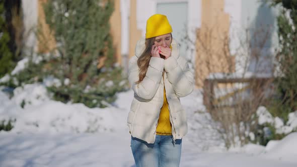 Young Freezed Caucasian Woman Standing Outdoors on Winter Day Talking on the Phone