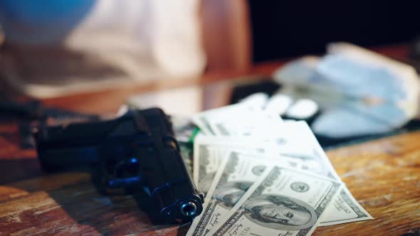 Gun, drugs and money. Drugs dealer stacks the heroin filled bags