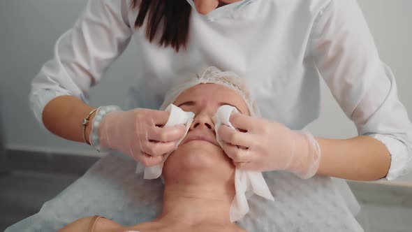 The Beautician Wipes the Face with Wet Wipes