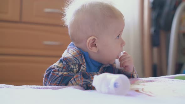 Little Boy Nibbles Part of Inhaler Standing Near Bed Closeup