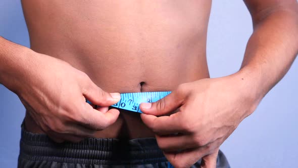 Young Man Measuring His Waist with a Tape Measure, Close Up