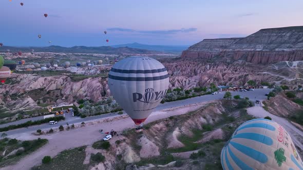 Hot air balloons fly over the mountainous landscape of Cappadocia, Turkey.