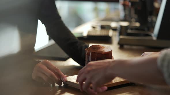 4K Asian woman barista serving iced chocolate with froth milk to customer