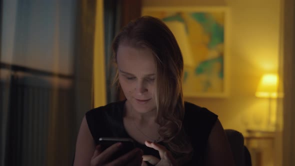 Happy young woman with cell at home in the evening