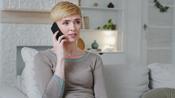 Happy Young Woman Sit in Living Room Holding Mobile Phone Call Provide Consultation Remotely Chat