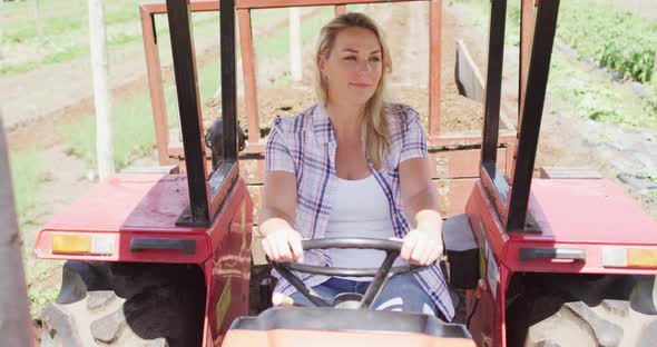 Video of happy caucasian woman driving tractor