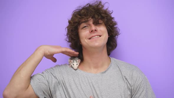A Man with Curly Hair with a Pet Ratmouse on an Isolated Background in the Studio
