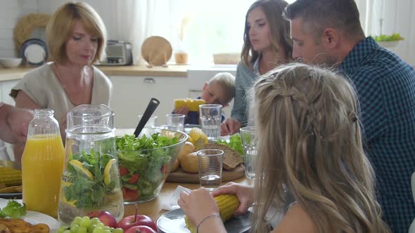 Attractive American Family Sharing Healthy Meal Together Sitting at Table in Home Interior