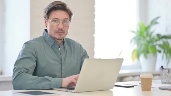 Middle Aged Man with Laptop feeling Shocked