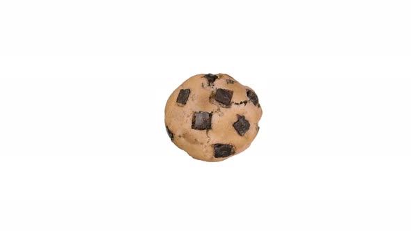 Freshly cooked chocolate chip cookie spinning on white background, top down view