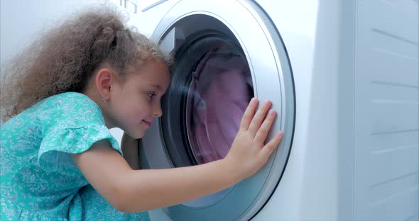 Cute Child Looks Inside the Washing Machine. Cylinder Spinning Machine. Concept Laundry Washing