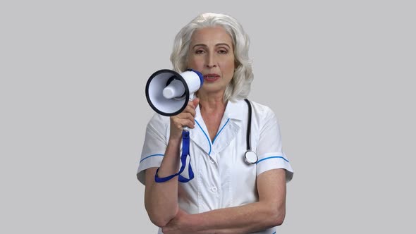 Portrait of Old Senior Female Doctor Speaking in Megaphone