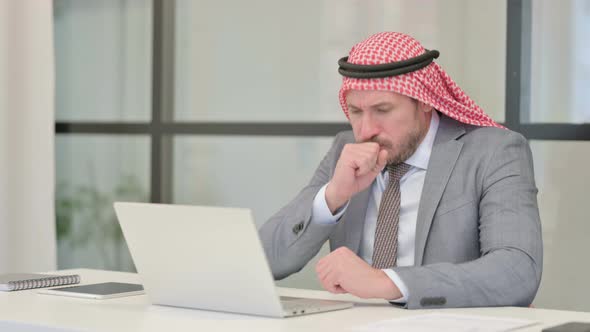 Middle Aged Arab Businessman Coughing while using Laptop in Office