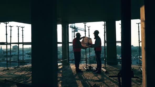 Engineers in Uniform Work with a Bluprint.