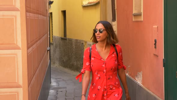 A woman walking in a red dress in a luxury resort town in Italy, Europe.