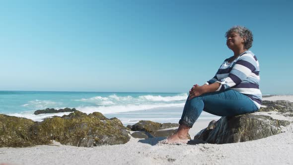 Senior woman sitting on a rock at the beach