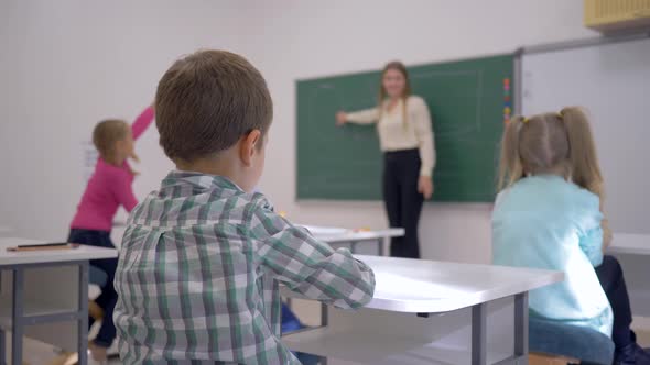 Children Education, Schoolkids at Lesson Listen To Teacher at Blackboard in Focused in Classroom of