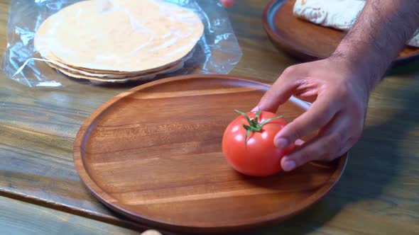 Men's Hands Beautifully Spread Tomatoes on a Wooden Round Cutting Board