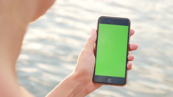 NICE, FRANCE - JULY 2017 Green screen smart phone  in woman hands at the beach