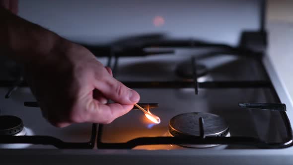 A man lights a gas stove with a match