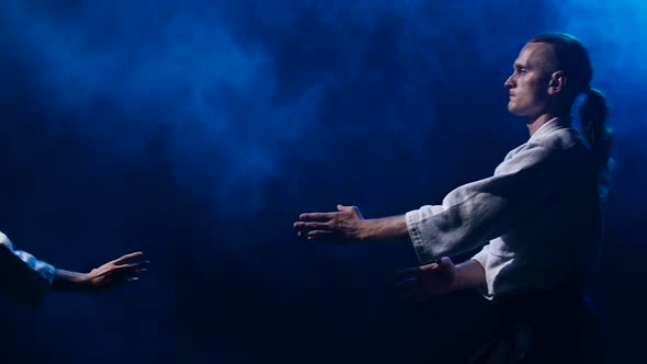 Fight Between Two Aikido Fighters in Dark Studio with Smoke and Lighting. Slow Motion. Close Up.