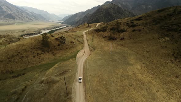 A White Car Drives Offroad in a Mountainous Area