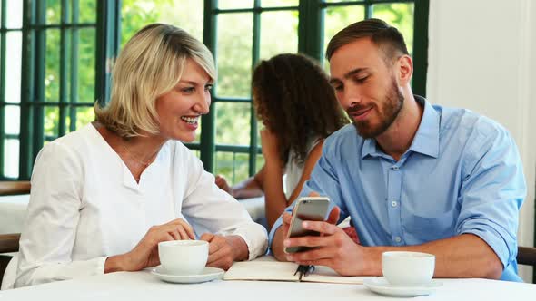 Male and female executives discussing over mobile phone 4k