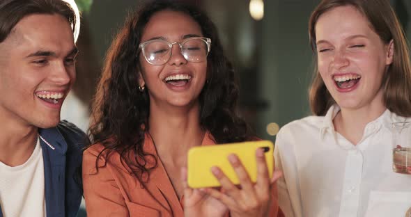 Close Up of Young Woman Holding Phone in Horizontal Landscape Mode While Showing Friends Funny