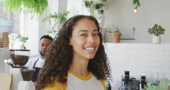 Portrait of happy biracial woman looking at camera and smiling at cafe