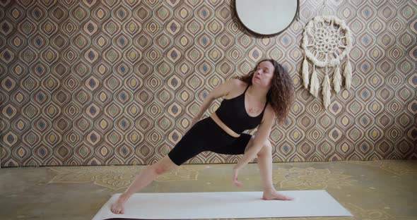 Sporty CurlyHaired Woman Does Yoga Stretching Exercises