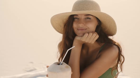 Woman with Coconut Relaxing on the Beach