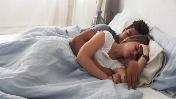 Multiracial Couple Lying in Bed and Sleeping While Embracing Each Other