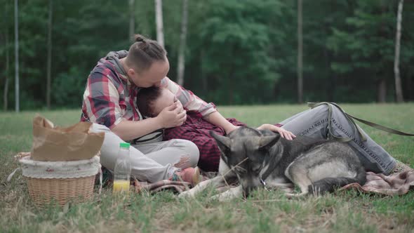 Relaxed Young Woman Lying on Knees of Loving Man with Dog at Front. Portrait of Happy Carefree