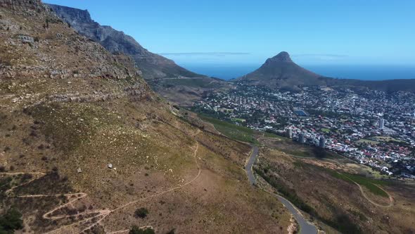 Drone shot of Cape Town - drone is reversing near Woodstock Cave at Table Mountain, facing Lions Hea