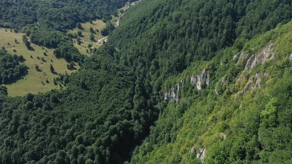 Flying Above a Deep Valley and Deciduous Forest and Limestone Cliffs. Aerial Shot