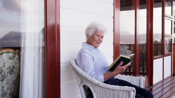 Woman reading a book in balcony at home 4k