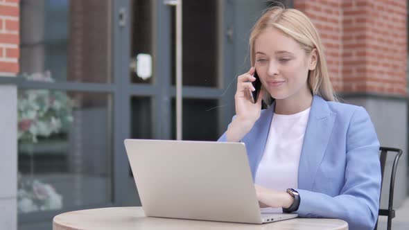 Young Businesswoman Talking on Phone, Sitting Outdoor