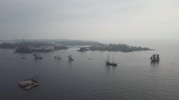 Aerial footage of tradtional wooden sailing ships sailing in front of port of Helsinki Finland